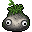 A funny-shaped grey rock, with moss growing on its top like hair. Someone has pasted googly eyes on it, and drawn a silly mouth on it with marker.