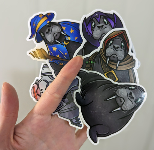 a photo of a hand holding some large, glossy stickers of walruses