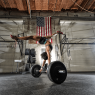 A dark-skinned woman wearing a matching grey-and-black sports bra and work-out shorts.  She's in a handstand holding on to a barbell. Her right leg is forward, her left leg back.  There's nothing keeping the barbell from moving.