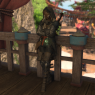 A screenshot. Clydwyn leans against a railing inside a bar in Tuliyollal. He wears a monster hunter's regalia and his face is partially obscured by a hood. His wings are hidden.